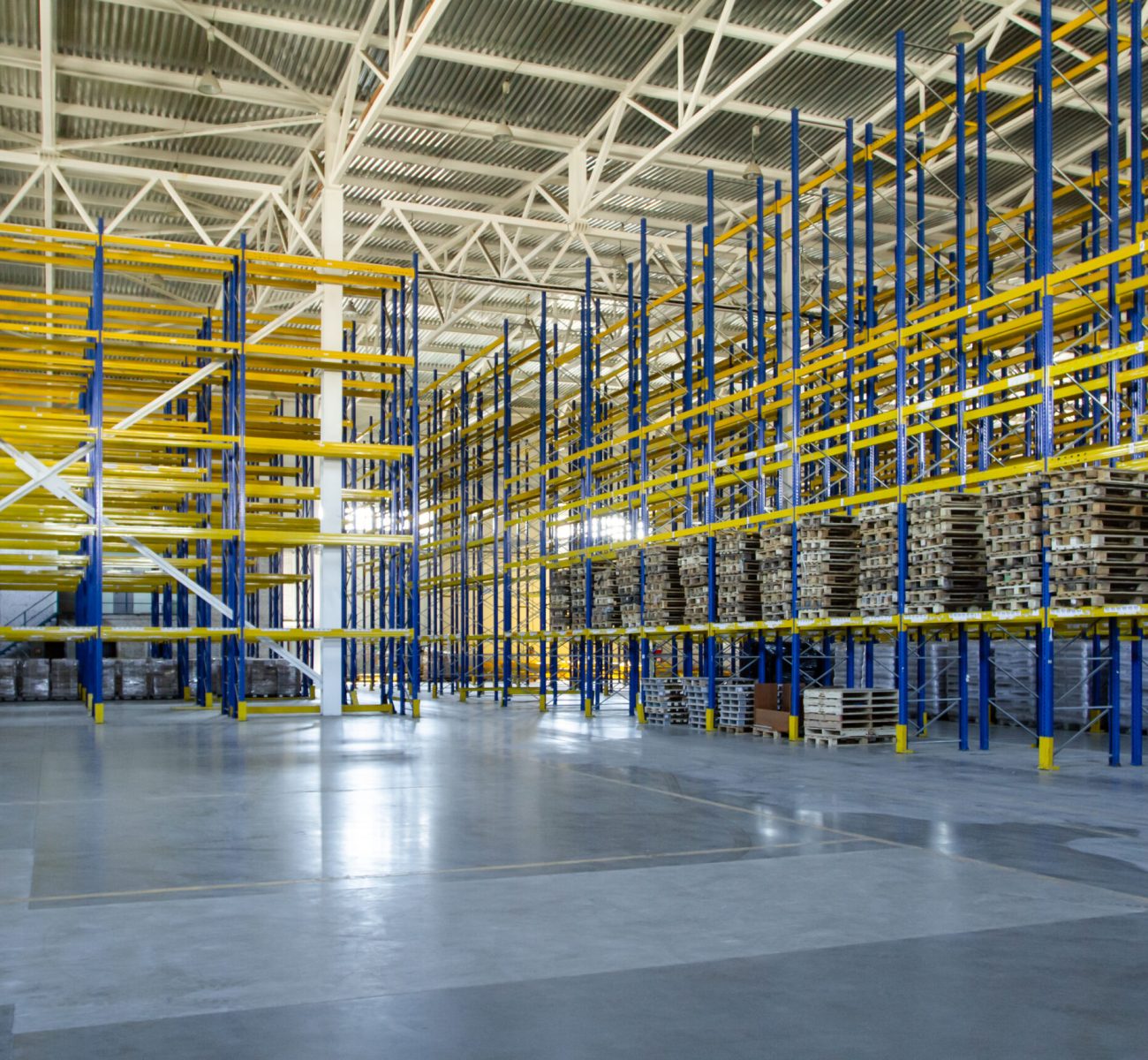 Interior of a modern warehouse storage of retail shop with pallet truck near shelves. Rows of steel shelves and racks Interior of a modern warehouse storage of retail shop with pallet truck near shelves. Rows of steel shelves and racks